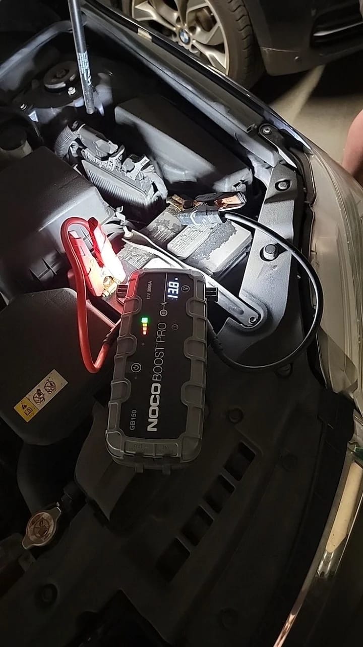 Jump starter connected to a car battery under the bonnet